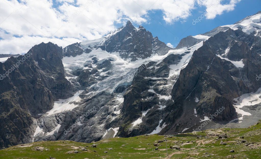 Breathtaking shot of the La Meije glacier towering above a large empty meadow.