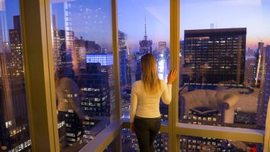 Tanımlanamayan genç kadın New York 'un akşam siluetini gözlemliyor..