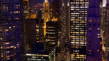 Geceleri New York 'un hareketli caddelerinin üstündeki yüksek katlı ofis binaları.