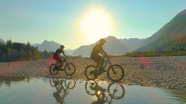 CHIUSURA: Raggi di sole dorati brillano su due viaggiatori che esplorano la valle in ebike. — Foto Stock