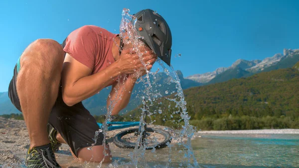 FECHAR UP: Ajuste o homem no passeio de bicicleta espirra água corrente refrescante em seu rosto. — Fotografia de Stock