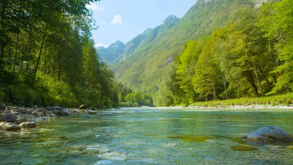 Rustige Soca rivier stroomt langzaam langs de weelderige groene bossen onder de bergen — Stockfoto