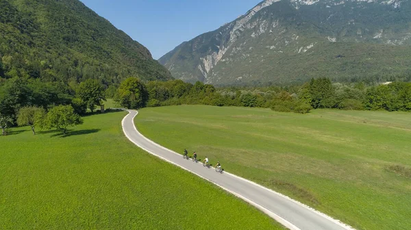 DRONE: Young travelers ride electric bicycles along an empty asphalt road. — 图库照片