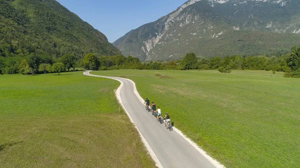 AERIAL: Μια ομάδα ταξιδιωτών βόλτα με ποδήλατα κατά μήκος του γραφικού δρόμου στην καταπράσινη κοιλάδα — Φωτογραφία Αρχείου