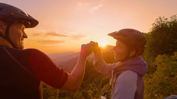 CHIUSURA: Felice uomo e donna pugni urto dopo un giro panoramico in bicicletta al tramonto. — Foto Stock