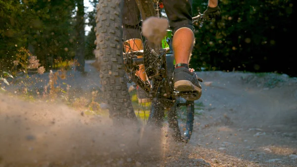 LÅG ANGLE: Man på grön mountainbike sparkar upp damm medan fortkörning utför. — Stockfoto