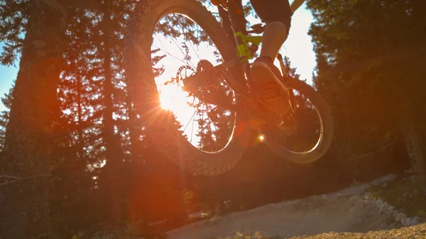 LENS FLARE: Filmový záběr extrémního horského motorkáře skákajícího z dřevěného kopáče — Stock fotografie