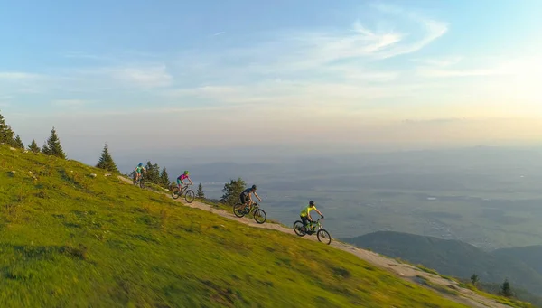 AERIAL: Flyger över fyra vänner rider sina mountainbikes ner smal stig. — Stockfoto
