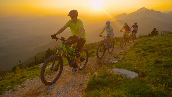 DRONE: Grupp turister ridning elektriska cyklar upp en naturskön stig vid solnedgången. — Stockfoto