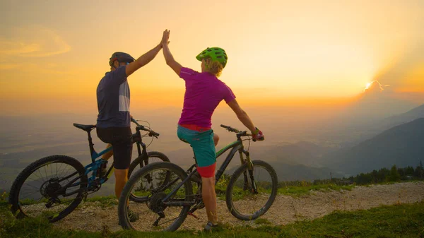 Neşeli arkadaşlar, başarılı bisiklet sürüşünden sonra gün batımında beşlik çakın.. — Stok fotoğraf