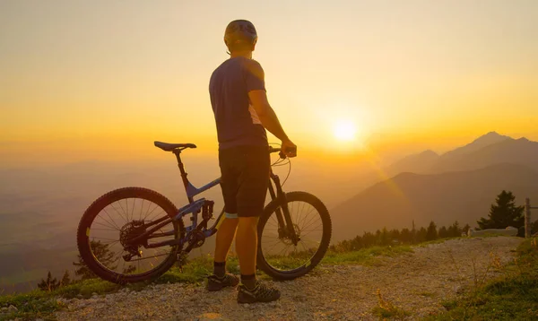 Tanınmayan adam, dağ bisikleti sürmeden önce güneşin doğuşunu izliyor.. — Stok fotoğraf