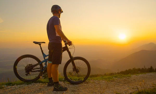 Güneş Işığı Adam, güneş ışığını gözlemlerken dağ bisikletinin yanında duruyor. — Stok fotoğraf
