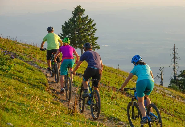 Fyra oigenkännliga vänner rider mountainbike uppför en solig morgon. — Stockfoto