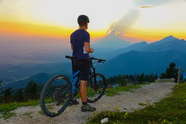 Irriconoscibile mountain bike osserva il tramonto da uno stretto sentiero di ghiaia. — Foto Stock