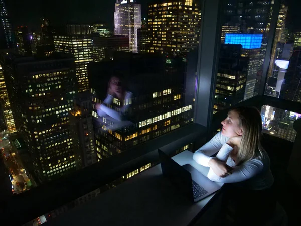FERMER : Étudiant travaillant tard dans la nuit regarde les gratte-ciel sombres. — Photo