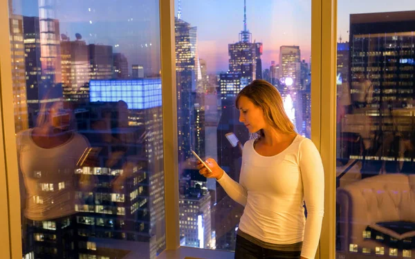 ПІДКАЗКА. Молода жінка пише своїм друзям смс на світанку зі свого готельного номера в Нью - Йорку.. — стокове фото