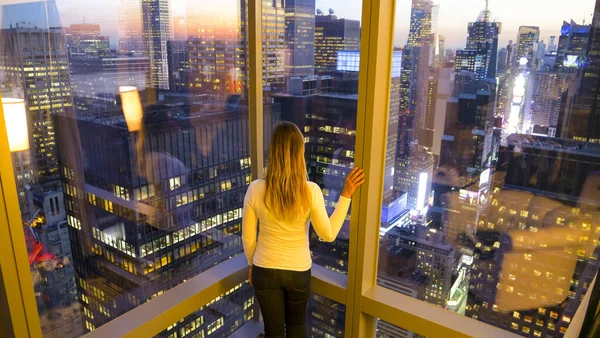 CLOSE UP: туристична дівчина стоїть біля вікон і спостерігає ранковий міський пейзаж . — стокове фото