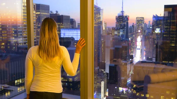 Vrouw kijkt uit op het adembenemende avondlandschap van New York City. — Stockfoto