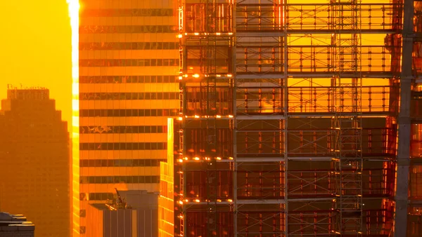 Sluiten: Gouden avond zon schijnt op steigers rond een wolkenkrabber — Stockfoto