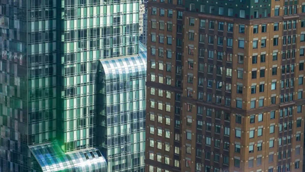 ZAMKNIJ SIĘ: Szklany wieżowiec i starszy brązowy wieżowiec w Nowym Jorku. — Zdjęcie stockowe
