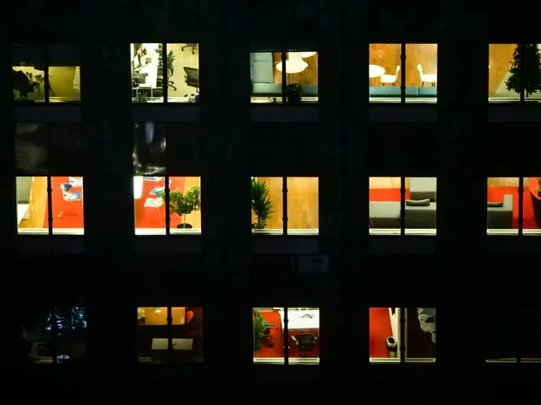 CLOSE UP: People extending their workdays late into the night in glassy building — Stock Photo, Image