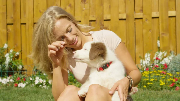 CERRAR UP Mujer alegre alimentando a su adorable cachorrito un regalo mientras se acaricia — Foto de Stock