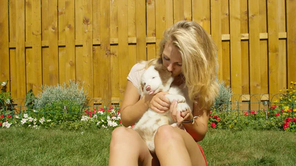 FECHAR UP: Jovem feliz desfrutando de um dia ensolarado e beijando seu filhote de cachorro adorável. — Fotografia de Stock