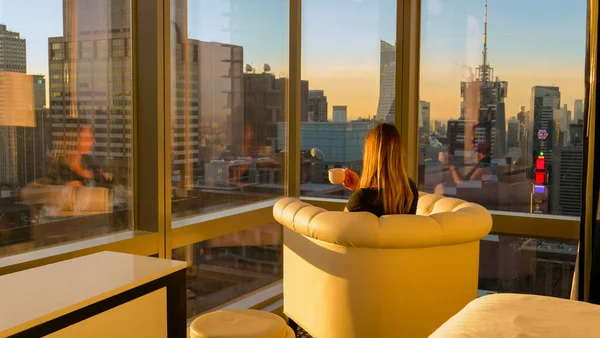 CLOSE UP: Woman having a cup of tea while observing the evening cityscape. Royalty Free Stock Images