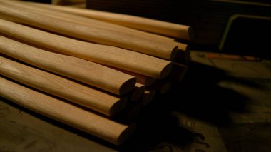CLOSE UP: Detailed view of long wooden tool handles resting on the work desk. clipart