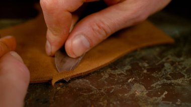 Keskin bir bıçakla ayakkabının altını kesen tanınmayan bir ayakkabı tamircisi.