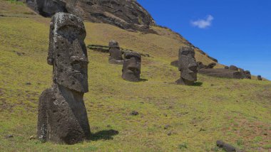 İnsanları andıran volkanik kayalardan yapılmış dört heykele doğru uçuyor..