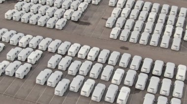 Beyaz kağıda sarılı sayısız araba büyük bir depolama parkına park edilmiş durumda.