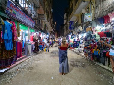Tanınmayan kadın turist yoğun bir gecede alışveriş caddesini gözetliyor..