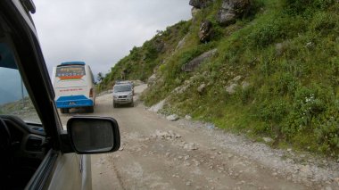 Nepal 'de seyahat eden bir cipin yanından geçerken bir turist otobüsünün arkasında sürmek.