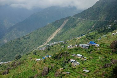 Himalaya 'daki tepelere dağılmış küçük kırsal evlerin üzerinde uçuyorlar..