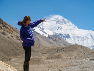 Neşeli Kafkasyalı kadın Everest Dağı 'nın rüzgarlı zirvesini işaret ediyor..