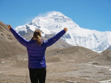 Trekker, Everest Dağı 'nı izlerken muzaffer bir şekilde kollarını açıyor.