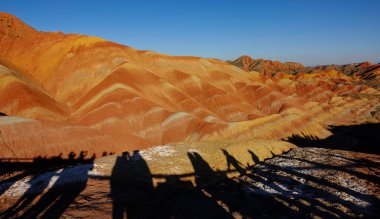 Geopark ziyaretçilerinin gölgeleri kayalık araziyi gözlüyor..