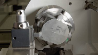 Küçük bir alüminyum parçası, kenarlarını tıraş etmek için bir CNC makinesi tarafından döndürülür.