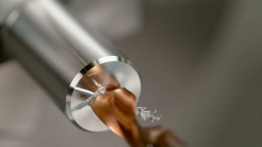 Sivri uçlu matkap ucu, metal bir çubuğun ortasında delik açıyor..