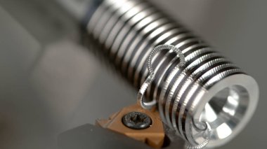 CNC makinesi yavaş yavaş küçük metal bir parçayı parlak bir vidaya sokuyor.