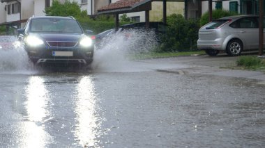 SUV banliyölerden geçerken kameraya kirli yağmur suyu sıçratır.