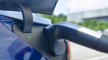 Boş aküsü olan bir arabaya takılı Tesla şarj cihazının ayrıntılı görüntüsü