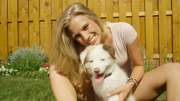 RETRATO: Mulher feliz desfruta de um dia de verão enquanto brinca com seu cachorro jovem. — Fotografia de Stock