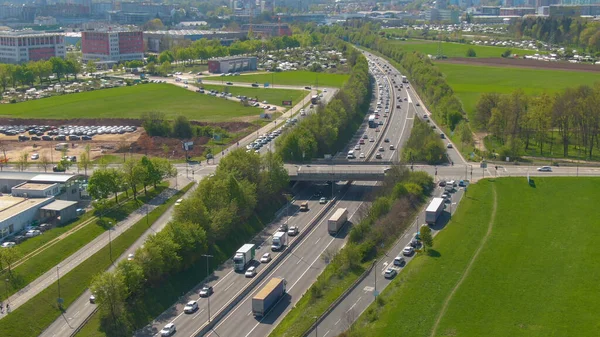 DRONE: Inúmeros veículos formam um engarrafamento na rodovia perto de uma cidade moderna. — Fotografia de Stock