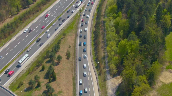 AERIAL: El tráfico congestionado se mueve a lo largo de un paso elevado y hacia un carril de entrada. —  Fotos de Stock