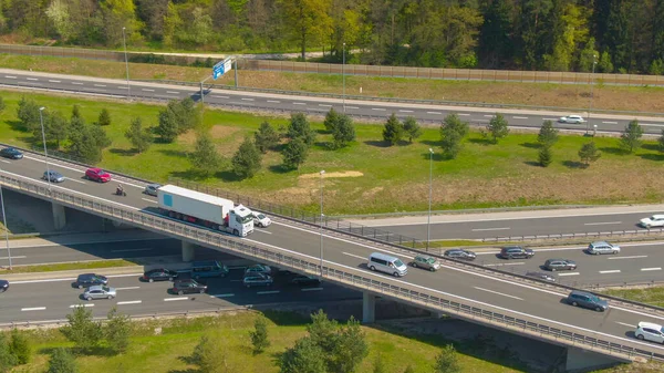 AERIAL: 18 wózków inwalidzkich przewożących kontener ładunkowy przez zatłoczoną autostradę — Zdjęcie stockowe