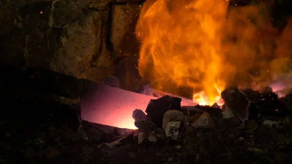 MACRO: Pessoa forjando uma lâmina puxa um pedaço de metal para fora da brasa ardente. — Fotografia de Stock
