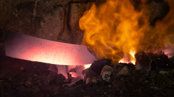 MACRO: Bladesmith puxa uma lâmina de faca brilhante do fogo queimando dentro do forno — Fotografia de Stock