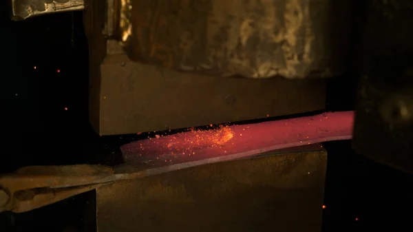 CLOSE UP: Orange sparks fly off the hot piece of metal being forged into blade. — Stock Photo, Image